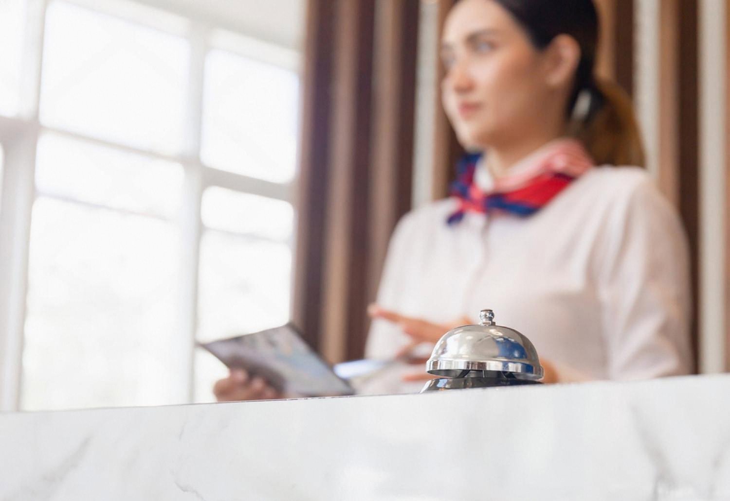 Service bell on a marble reception counter with a hotel staff member in the background