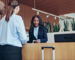 Hotel receptionist assisting two guests at a traditional front desk in a UAE hotel lobby