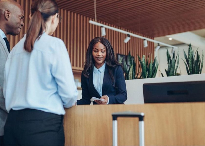 Hotel receptionist assisting two guests at a traditional front desk in a UAE hotel lobby